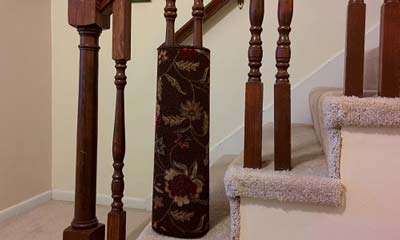 Flowered area rug wrapped around staircase spindle