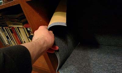 Hand attaching carpet to inside of bookshelf.